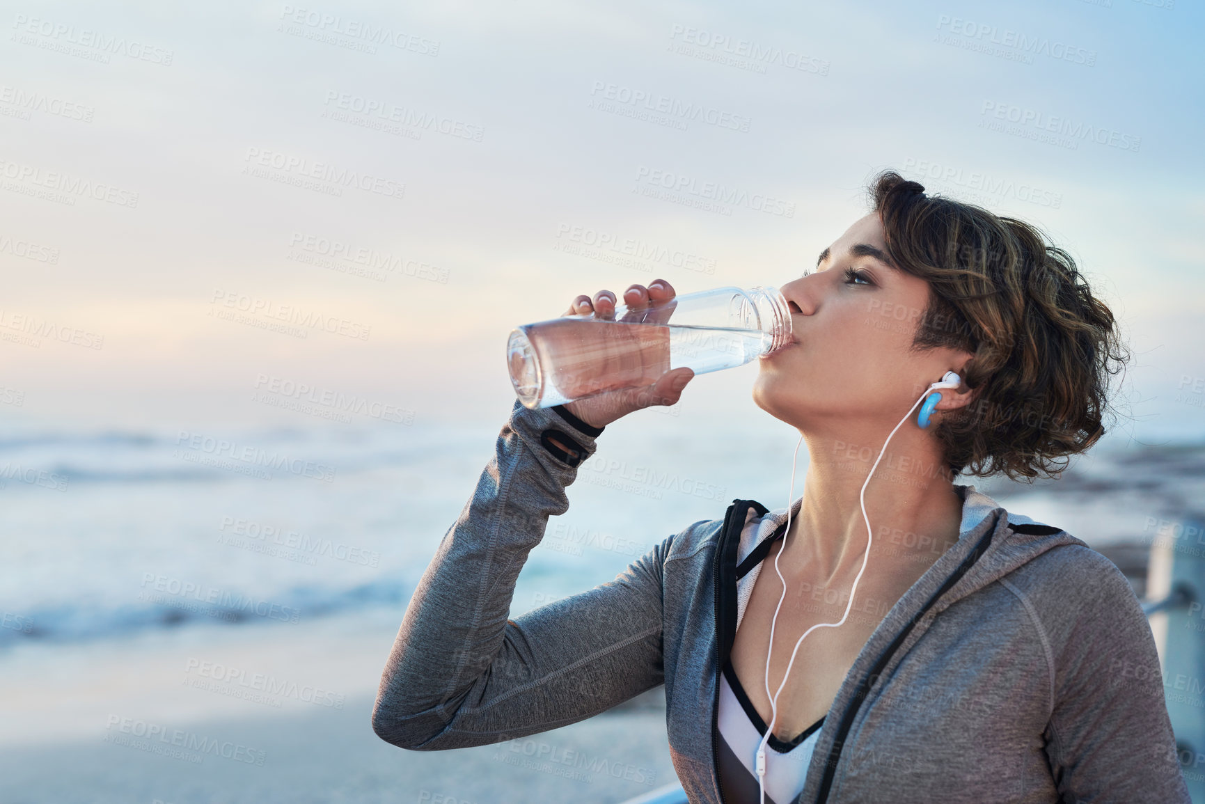 Buy stock photo Cropped shot of a young woman drinking water after her run