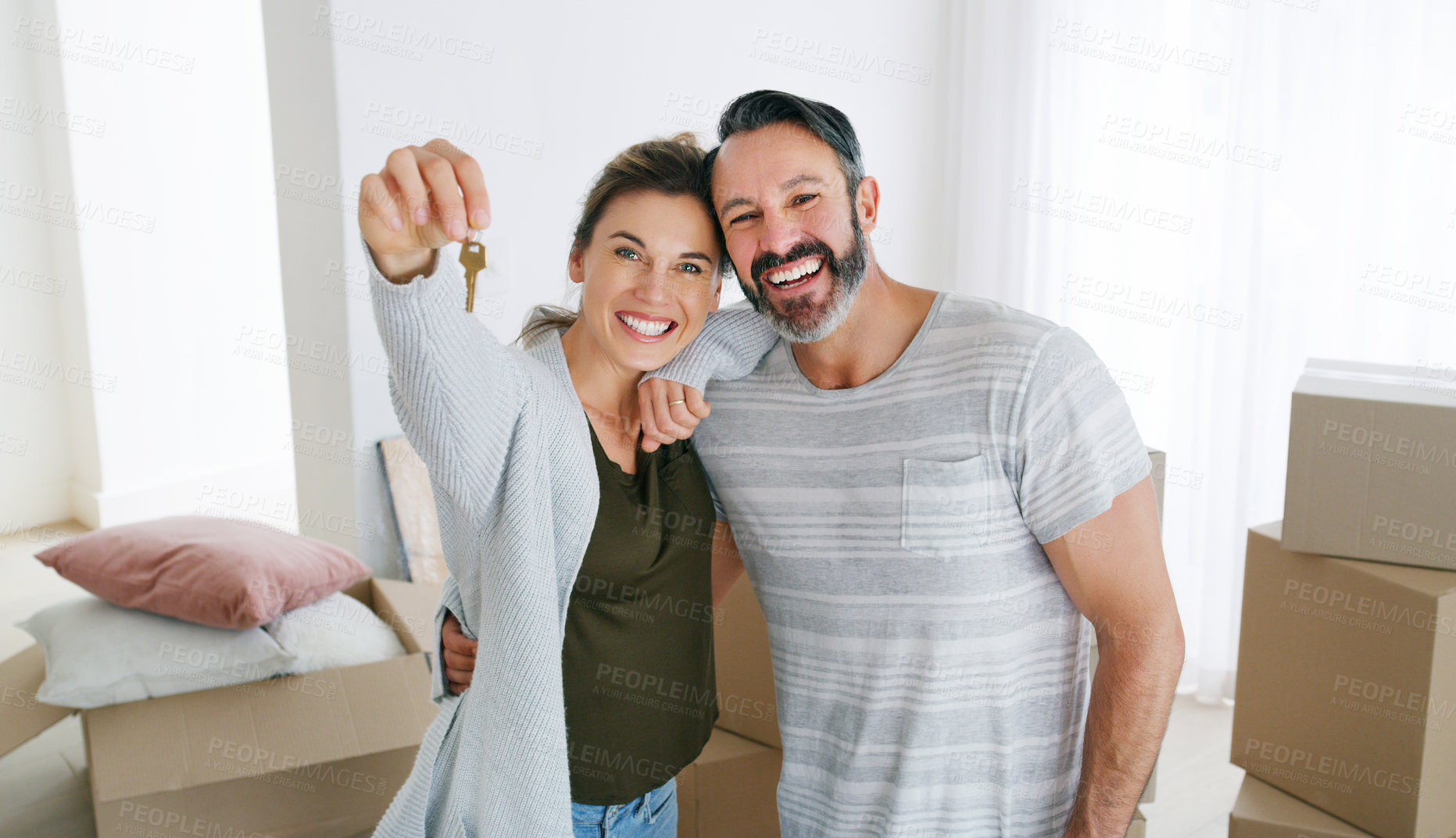 Buy stock photo Couple, portrait and happy with key in new home for property purchase, mortgage success and moving. Boxes, excited people and hug with keychain for achievement, relocation pride or investment support