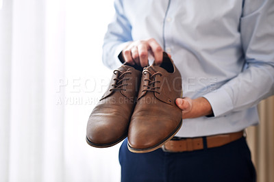 Buy stock photo Shot of an unrecognizable bridegroom holding the shoes he's going to wear inside a dressing room on his wedding day