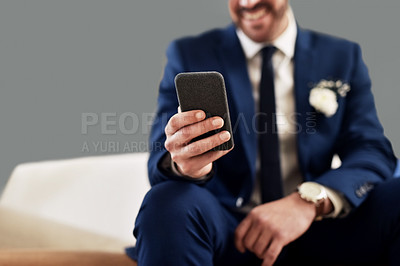 Buy stock photo Shot of an unrecognizable bridegroom using a cellphone while relaxing in the dressing room on his wedding day