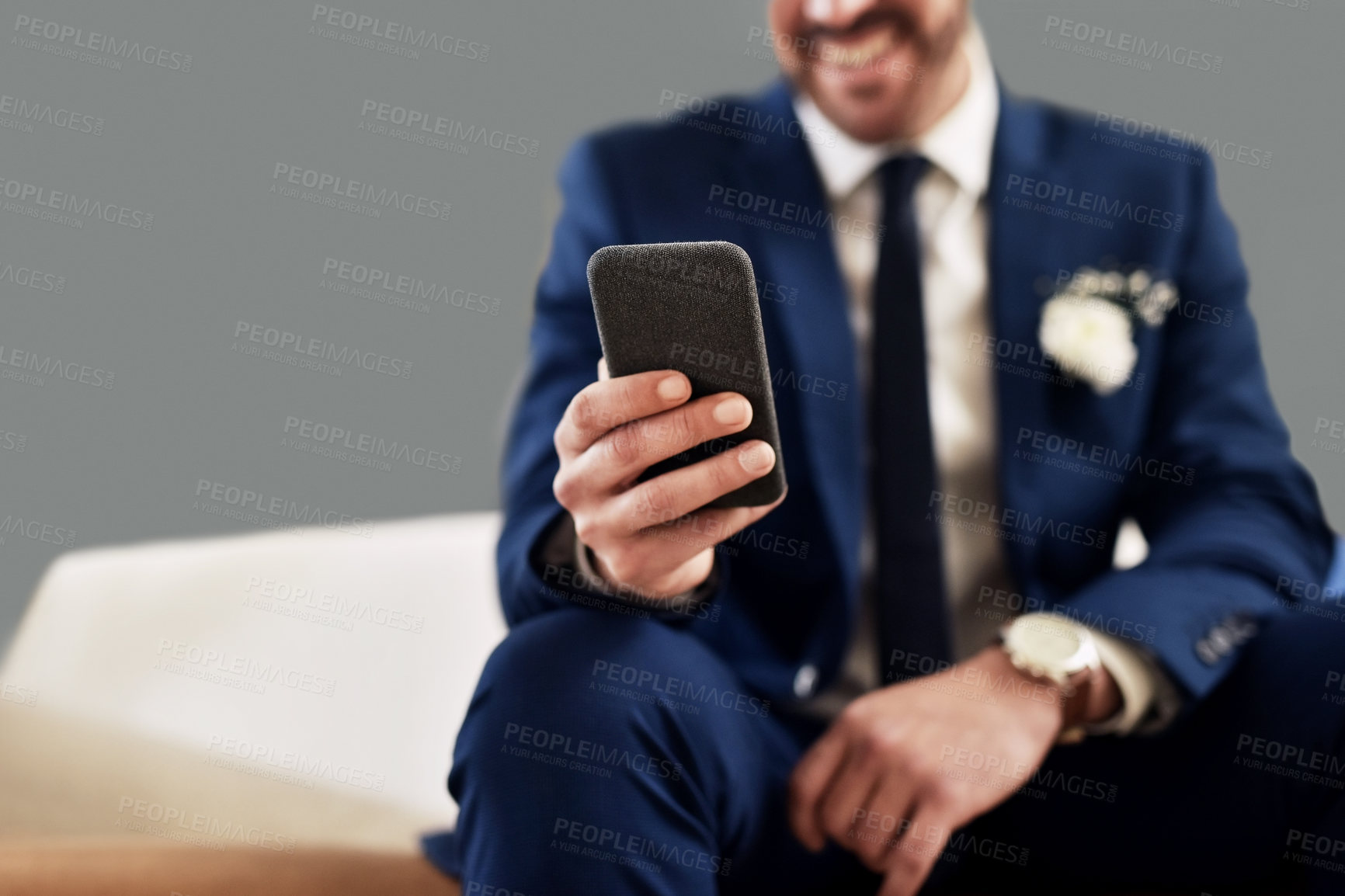 Buy stock photo Shot of an unrecognizable bridegroom using a cellphone while relaxing in the dressing room on his wedding day