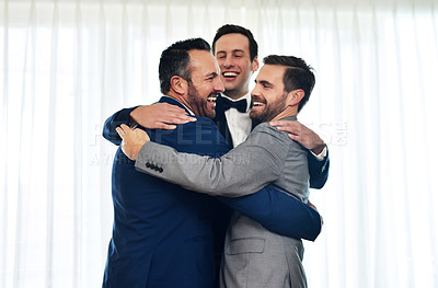 Buy stock photo Shot of two groomsmen hugging and celebrating with the bridegroom on his wedding way