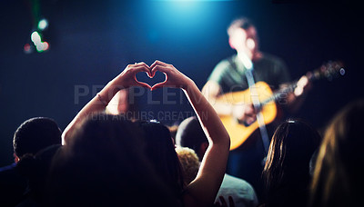 Buy stock photo Cropped shot of an unrecognizable woman's hands making a heart shape while a musician is performing at a concert at night