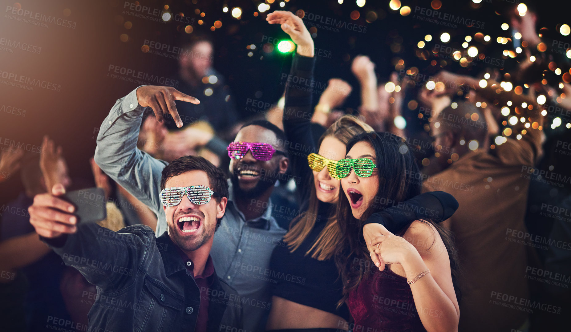 Buy stock photo Cropped shot of a diverse group of young friends taking a selfie together at a party at night