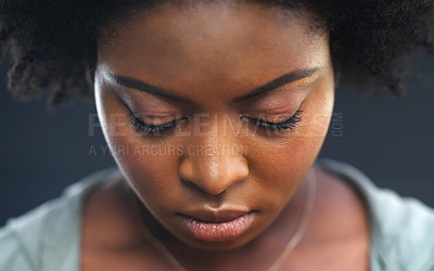 Buy stock photo Cropped shot of a young woman looking down against a dark background