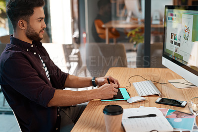 Buy stock photo Cropped shot of a handsome young businessman sitting alone in his office and editing images