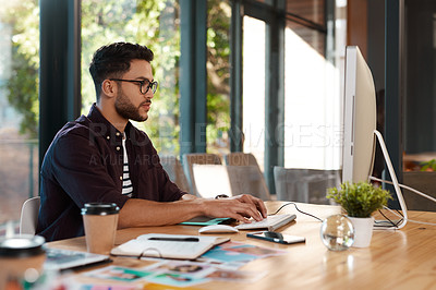 Buy stock photo Designer, man and typing online on computer while working at desk for research or creative work. Male entrepreneur person with glasses and focus for reading or writing email with internet connection