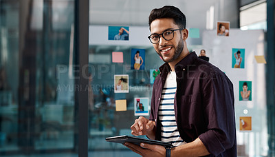 Buy stock photo Cropped portrait of a handsome young businessman standing alone in his office and using a tablet