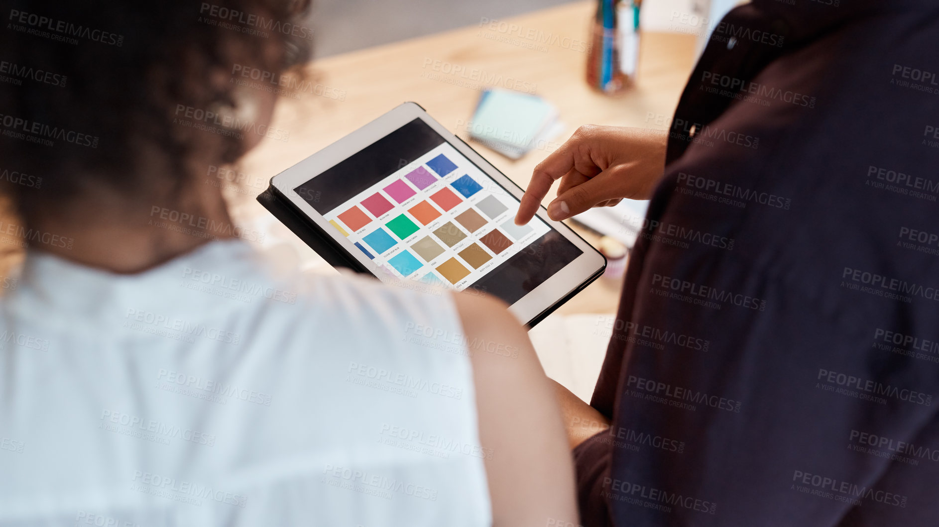 Buy stock photo Rearview shot of two unrecognizable business colleagues standing together and using a tablet to view colour swatches