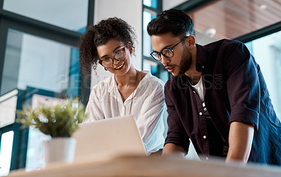 Buy stock photo Cropped shot of two young business colleagues standing together and using a laptop in the office