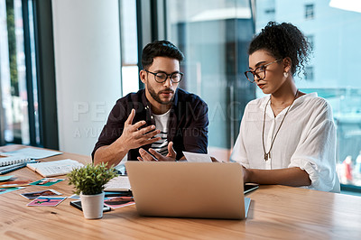Buy stock photo Cropped shot of two young businesspeople sitting together and having a discussion over polaroids in the office