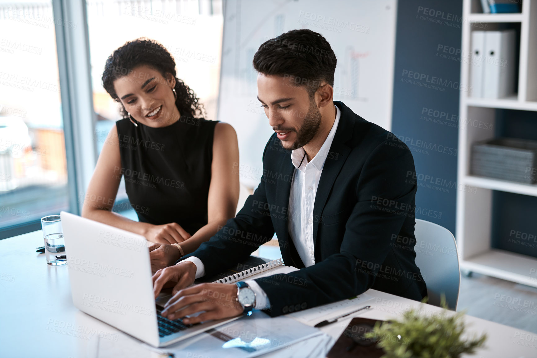Buy stock photo Cropped shot of two young business colleagues sitting together and using a laptop in the office