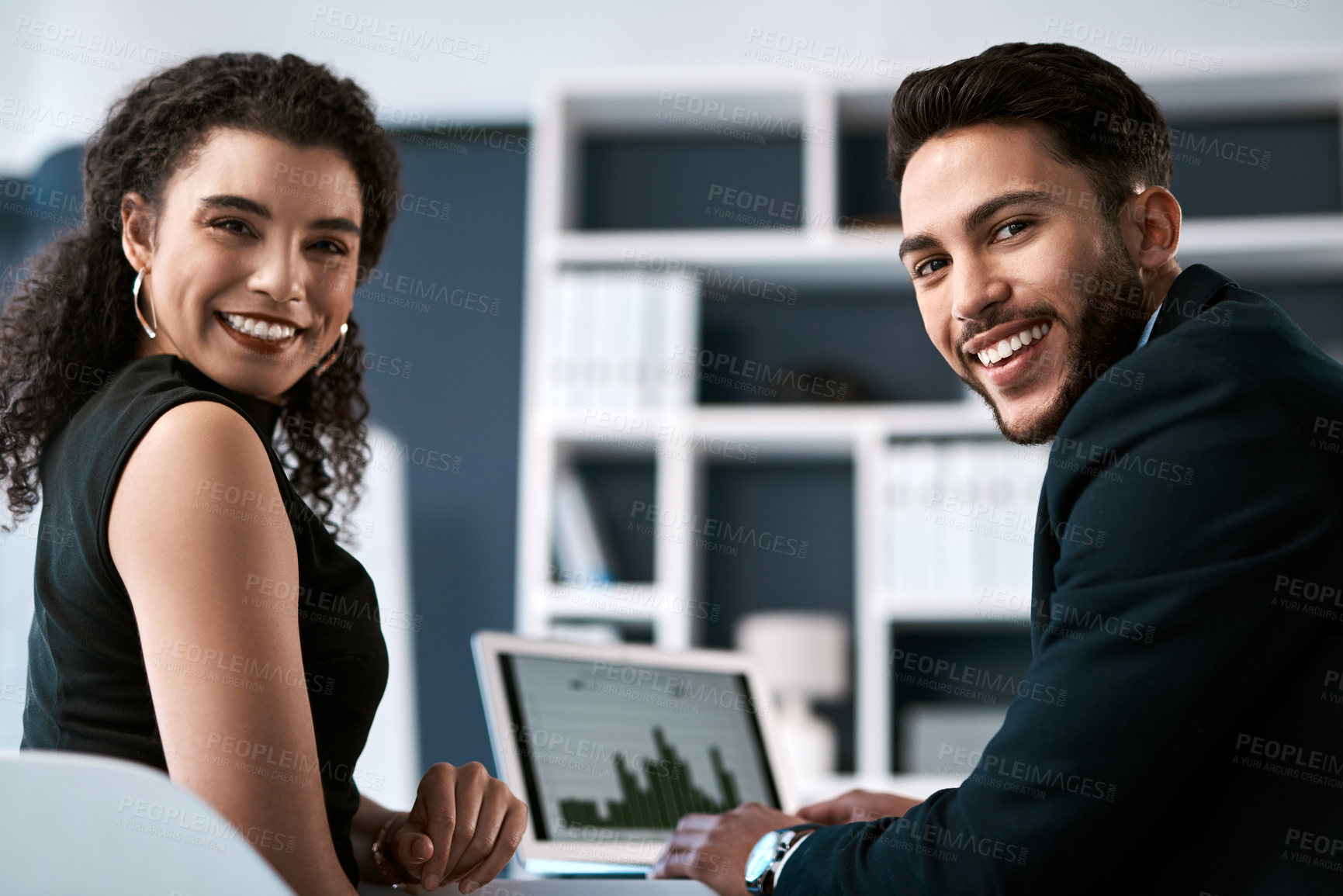 Buy stock photo Cropped portrait of two young businesspeople sitting together and having a discussion while using a laptop in the office