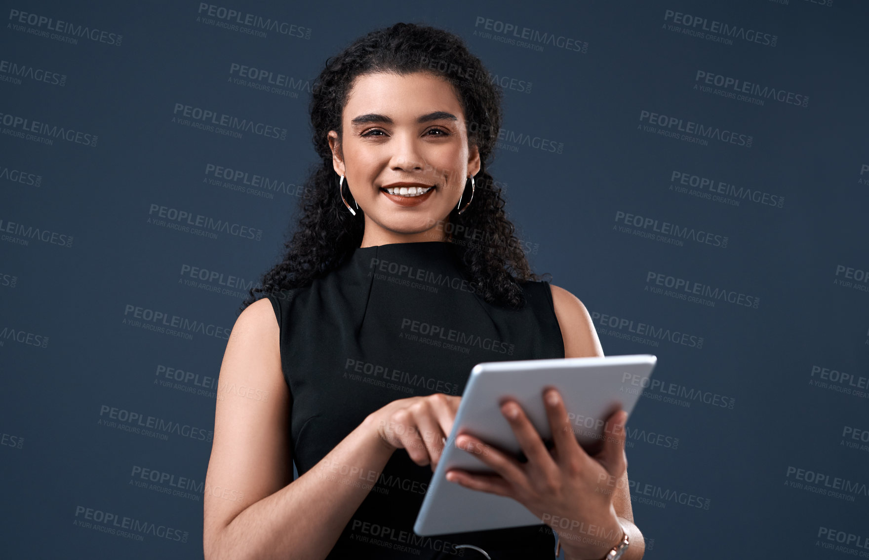 Buy stock photo Cropped portrait of an attractive young businesswoman standing alone and using a tablet against a gray background in the studio