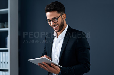 Buy stock photo Cropped shot of a handsome young businessman standing alone and using a tablet against a gray background in the studio