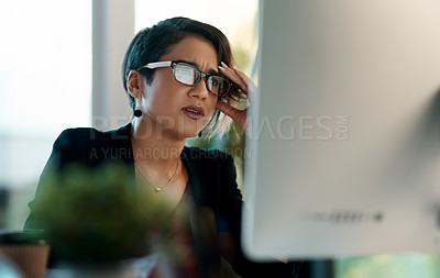 Buy stock photo Cropped shot of an attractive young businesswoman sitting alone and feeling stressed while working on her computer in the office
