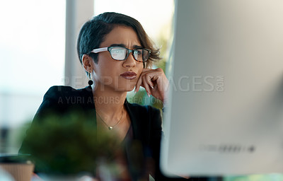 Buy stock photo Cropped shot of an attractive young businesswoman sitting alone and feeling overwhelmed while working on her computer in the office