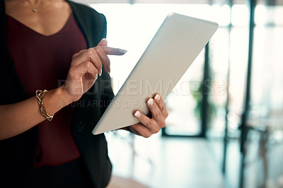 Buy stock photo Cropped shot of an unrecognizable businesswoman standing in her office alone and using a tablet