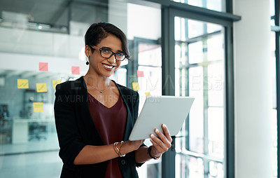 Buy stock photo Cropped portrait of an attractive young businesswoman standing alone in her office and working on a tablet