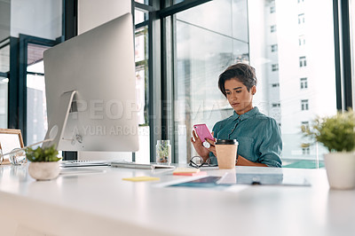 Buy stock photo Cropped shot of an attractive young businesswoman sitting alone in her office and texting on her cellphone