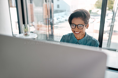 Buy stock photo Cropped shot of an attractive young businesswoman sitting alone and working on her computer in the office