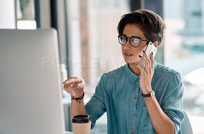 Buy stock photo Cropped shot of an attractive young businesswoman sitting in her office and talking on her cellphone while using her computer