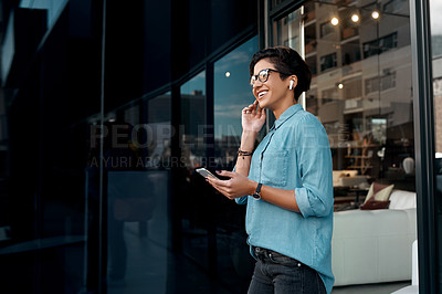 Buy stock photo Cropped shot of an attractive woman standing outside and putting her earpods in to listen to music through her cellphone