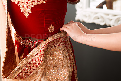 Buy stock photo Cropped shot of an unrecognizable maid of honour helping the bride with putting on her saree on the morning of the wedding