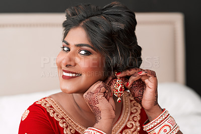 Buy stock photo Cropped portrait of a beautiful young bride putting on her earrings in preparation for her wedding