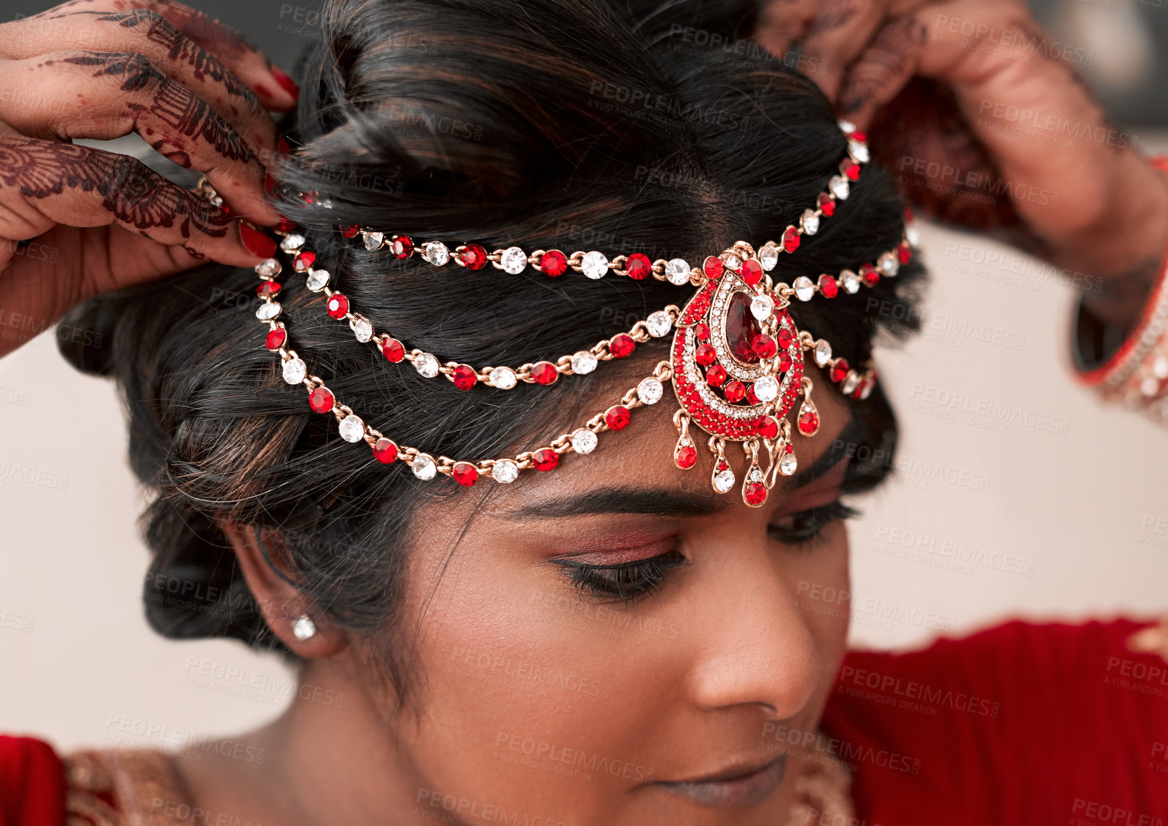 Buy stock photo Cropped shot of a beautiful young bride putting on a maang tikka headpiece in preparation for her wedding