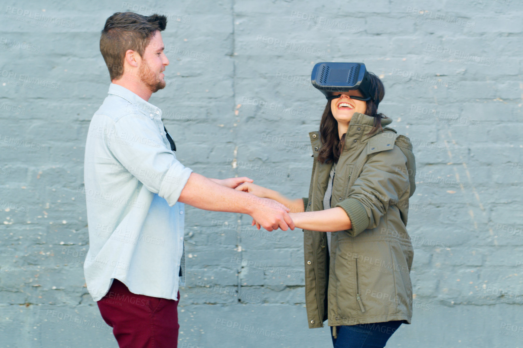 Buy stock photo Cropped shot of an affectionate young couple having fun and using a virtual reality headset together outdoors