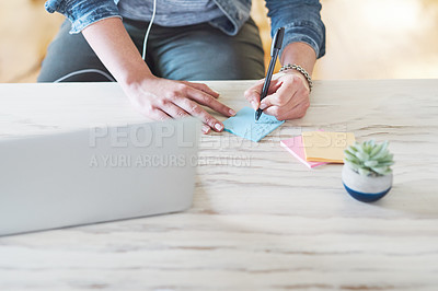 Buy stock photo Cropped shot of a businesswoman using a laptop and making notes at her desk in a modern office