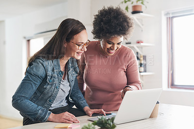 Buy stock photo Shot of two young businesswomen using a laptop in a modern office