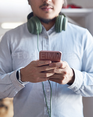 Buy stock photo Cropped shot of a young businessman using a smartphone in a modern office