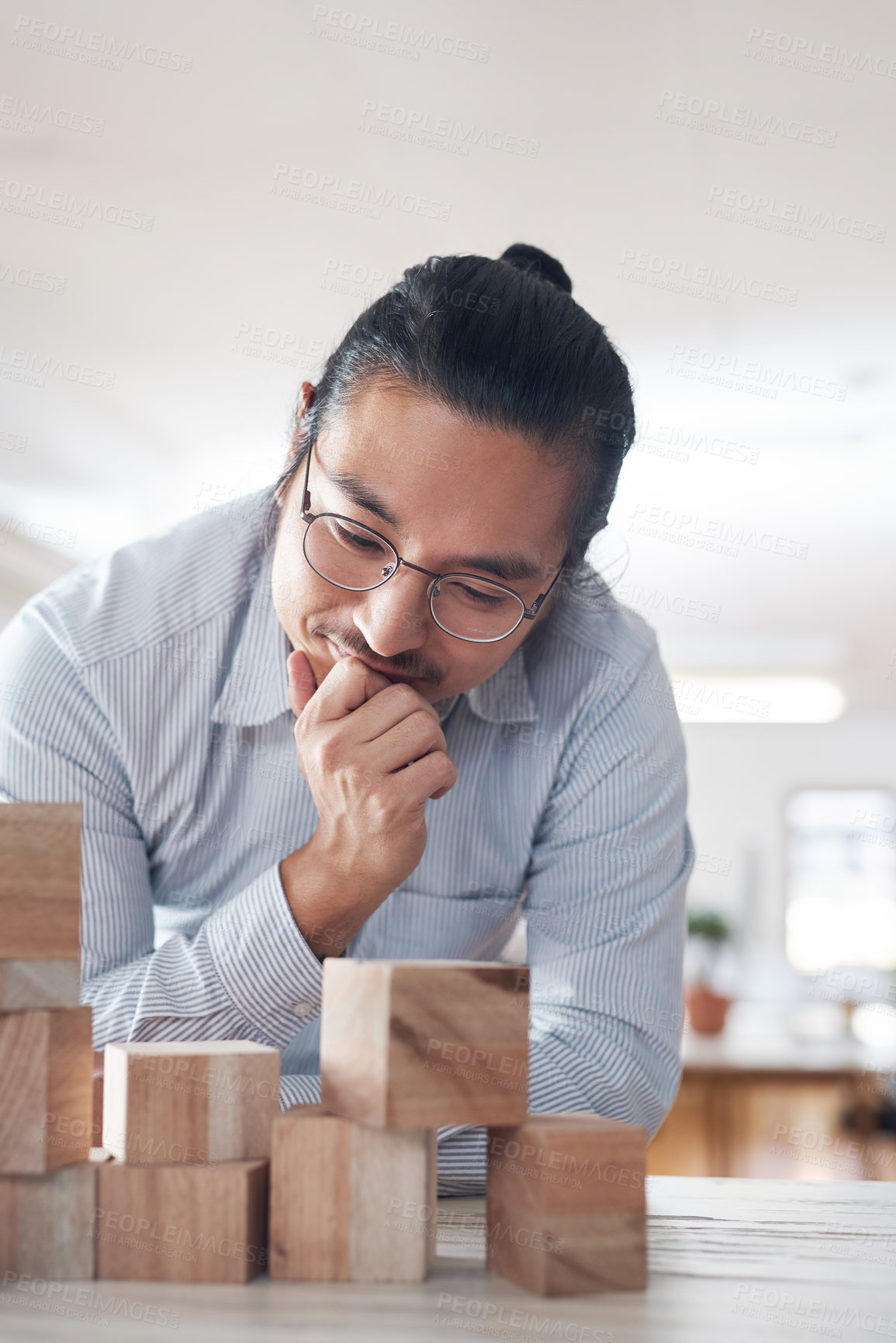 Buy stock photo Man in startup with building blocks, thinking of vision, games and design innovation for office or construction. Engineering, architecture and Asian designer with wood block for problem solving game.