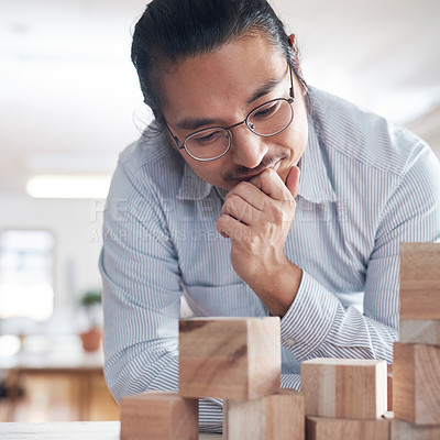 Buy stock photo Thinking, ideas and Asian man in office with building blocks, strategy game and design balance with innovation. Engineering, architecture and designer with idea, wood block game and problem solving.