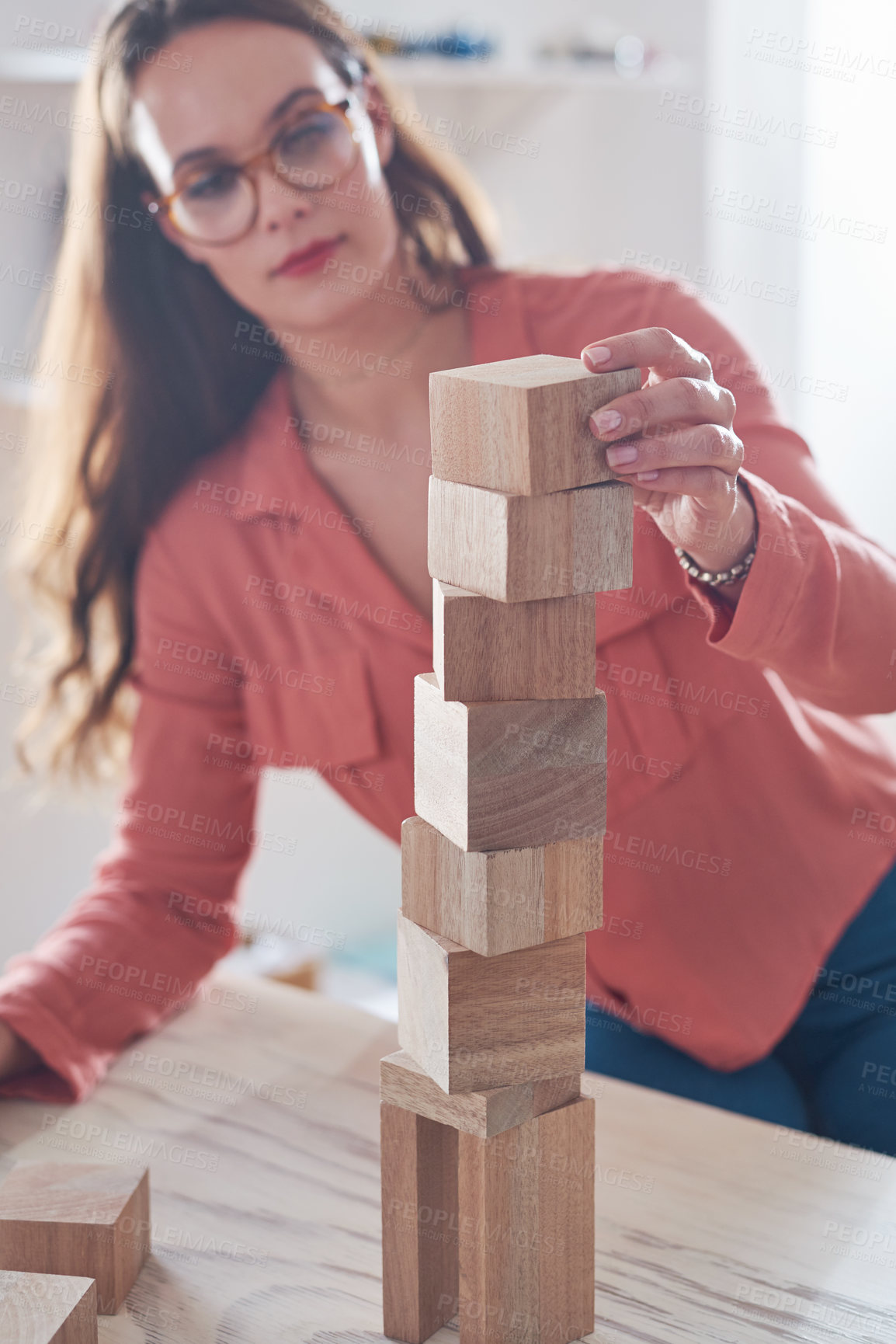 Buy stock photo Shot of a young businesswoman working with wooden building blocks in a modern office