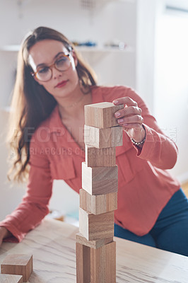 Buy stock photo Shot of a young businesswoman working with wooden building blocks in a modern office