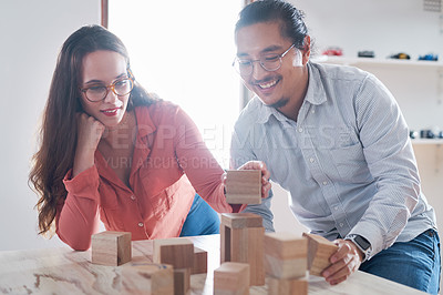 Buy stock photo Shot of a young businessman and businesswoman having a meeting with building blocks in a modern office