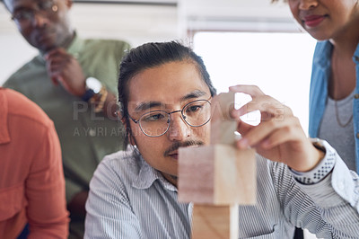 Buy stock photo Shot of a group of young businesspeople having a meeting with building blocks in a modern office