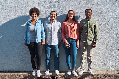 Buy stock photo Shot of a group of young people standing together against an urban background outdoors
