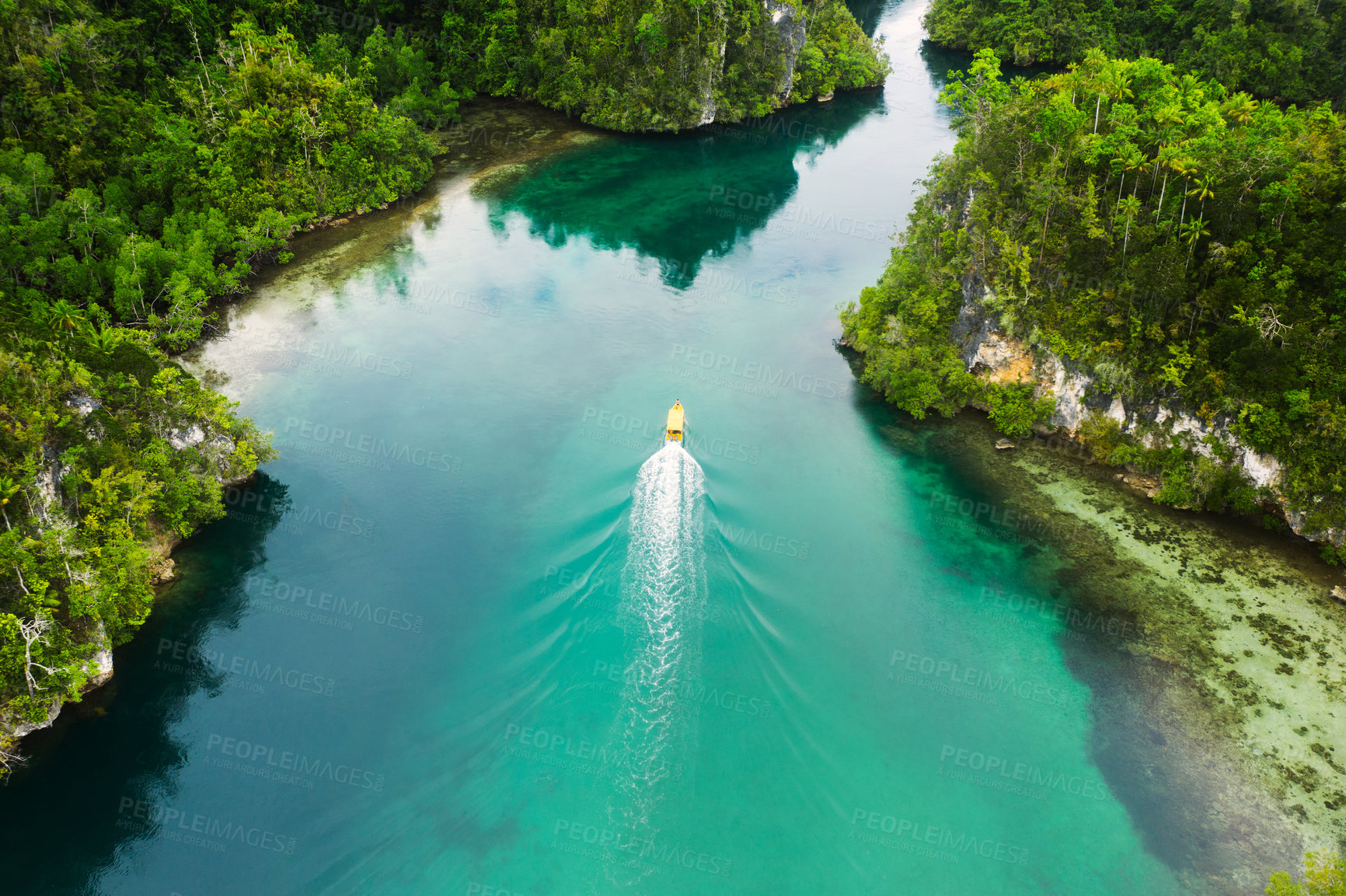 Buy stock photo High angle shot of a boat sailing through a canal running along the Raja Ampat Islands in Indonesia