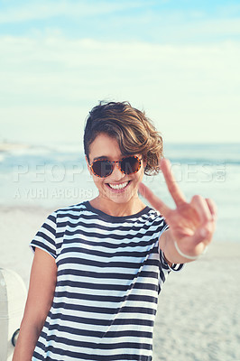 Buy stock photo Shot of a young woman showing the peace sign while standing outdoors on a sunny day
