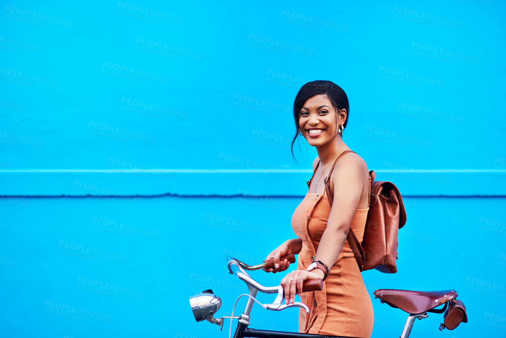 Buy stock photo Portrait of an attractive young woman traveling with her bicycle against a blue background