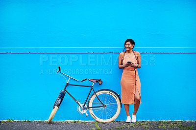 Buy stock photo Bicycle, young woman with smartphone and happy outside by blue wall. Cycling in urban area, health wellness and female person on cellphone outdoors standing in streets with bike or cycle in road