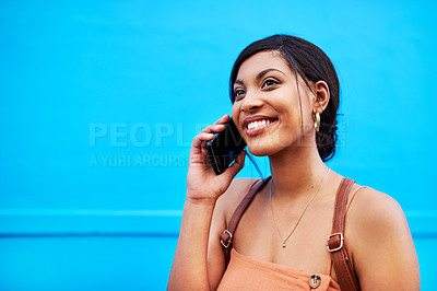 Buy stock photo Shot of an attractive young woman making a phone call against a blue background