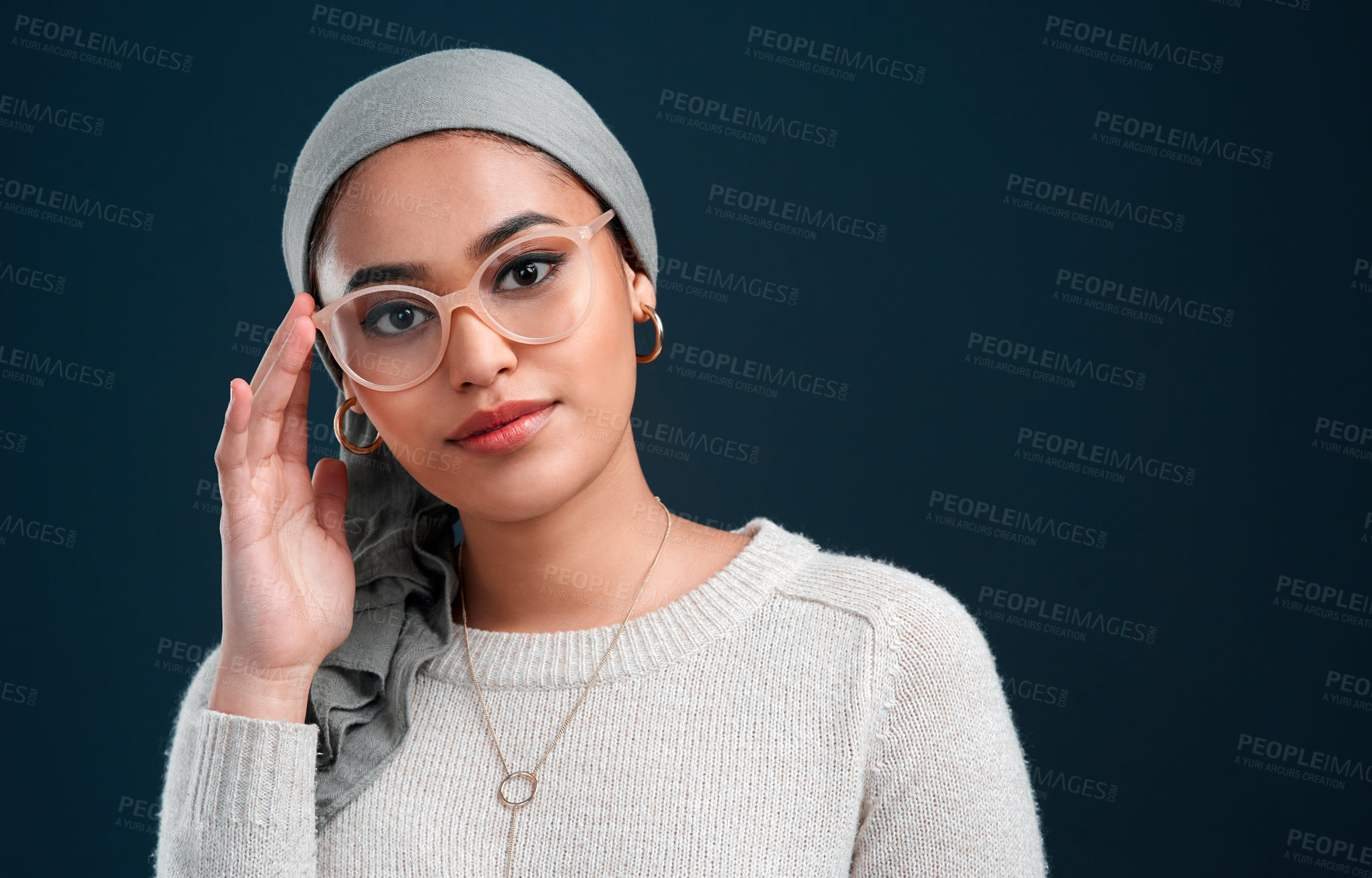 Buy stock photo Cropped shot of an attractive young woman standing against a black background alone while wearing spectacles and a headscarf