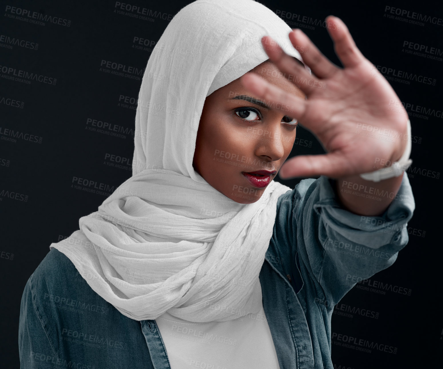 Buy stock photo Cropped shot of an attractive young woman wearing a hijab and raising her hand while standing against a black background