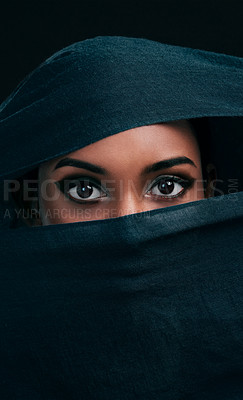 Buy stock photo Cropped shot of an attractive young woman wearing a hijab and only exposing her eyes while against a black background