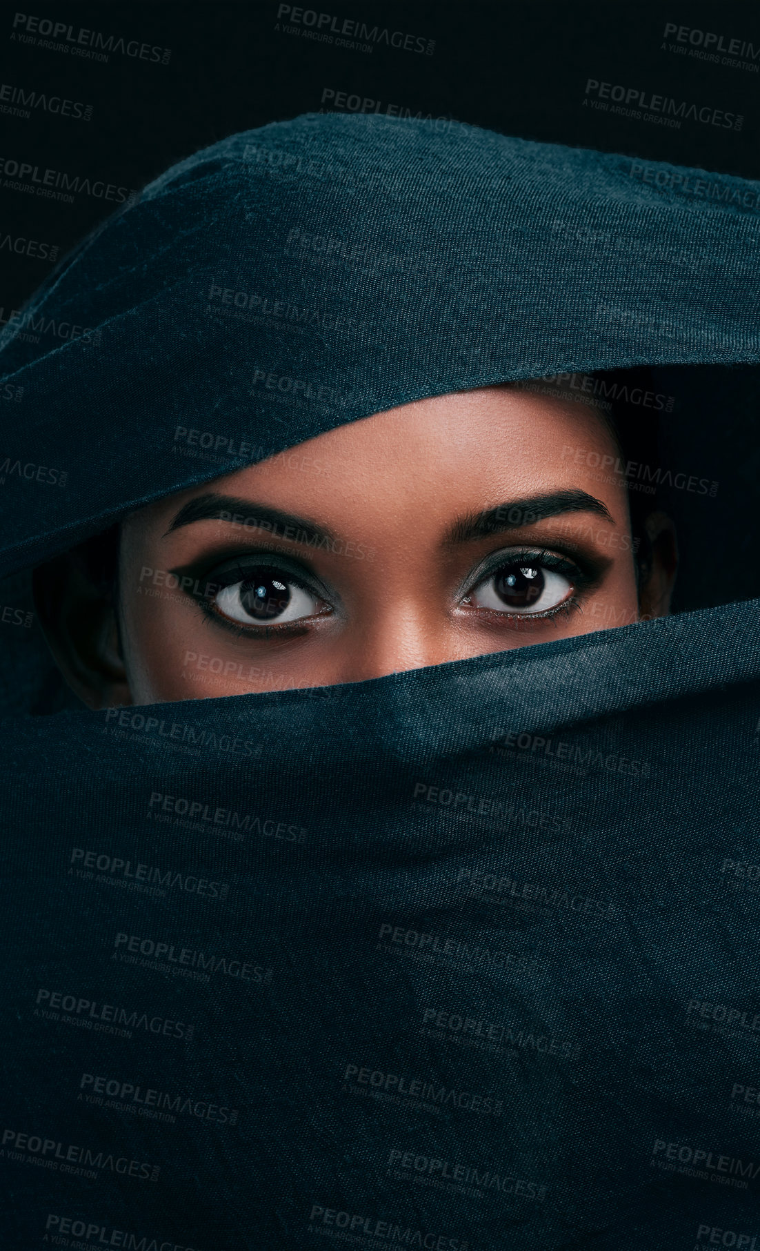 Buy stock photo Cropped shot of an attractive young woman wearing a hijab and only exposing her eyes while against a black background